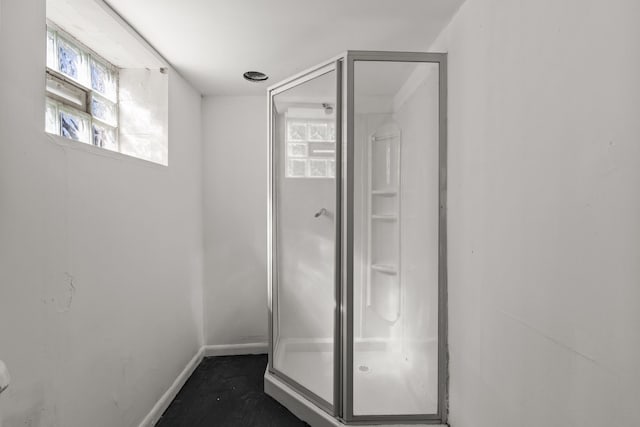 full bathroom featuring baseboards and a shower stall