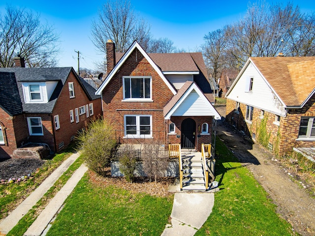 view of front of property with a chimney, a front lawn, and brick siding