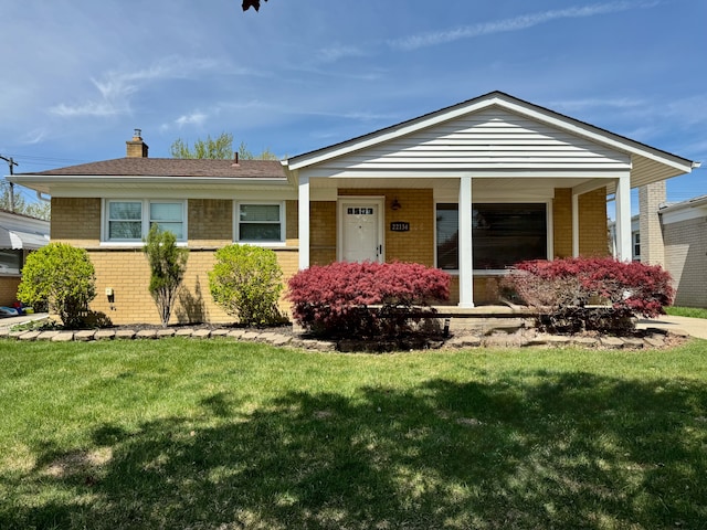 single story home featuring brick siding, a front lawn, a chimney, and a porch