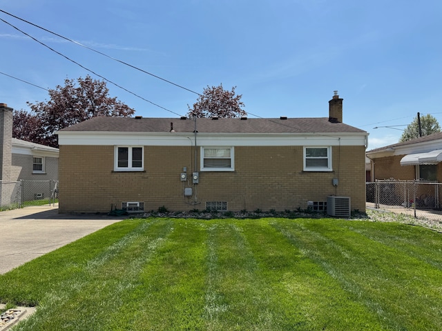 back of house featuring a yard, brick siding, and fence