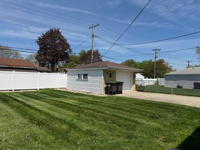 view of yard featuring concrete driveway, fence, an outdoor structure, and a garage