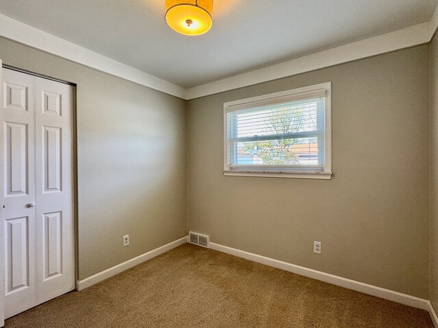 unfurnished bedroom with baseboards, carpet, a closet, and visible vents