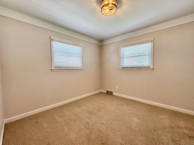 carpeted empty room featuring baseboards and visible vents
