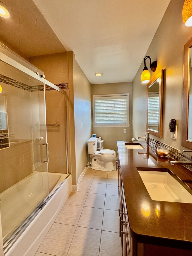 bathroom with toilet, combined bath / shower with glass door, a sink, and tile patterned flooring
