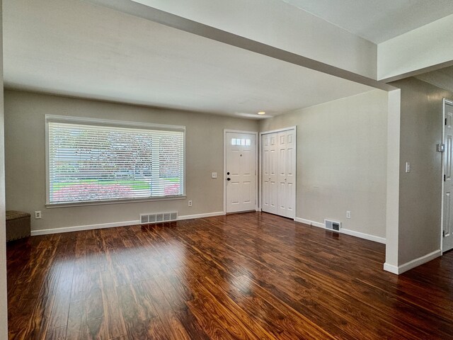 unfurnished living room with wood finished floors and visible vents