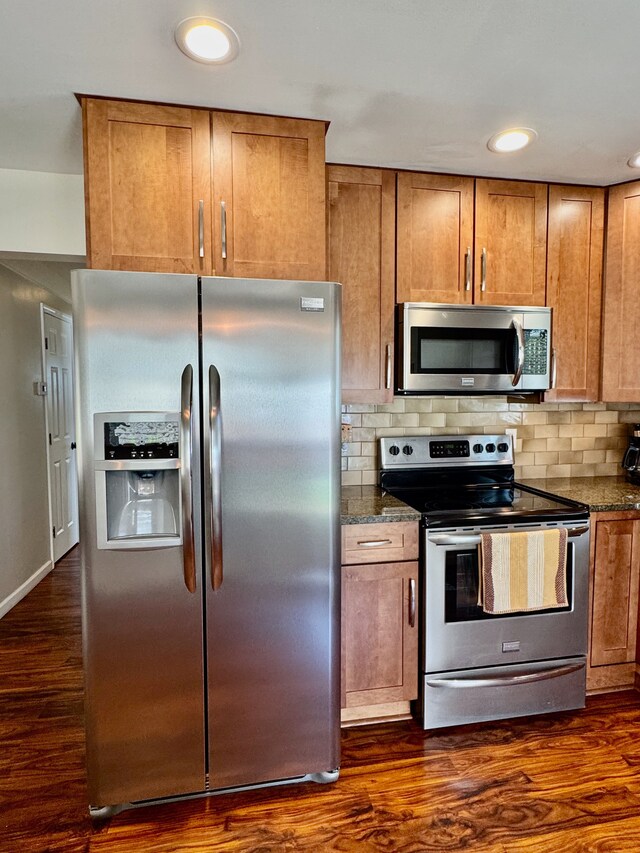 kitchen featuring appliances with stainless steel finishes, brown cabinets, and dark wood-type flooring
