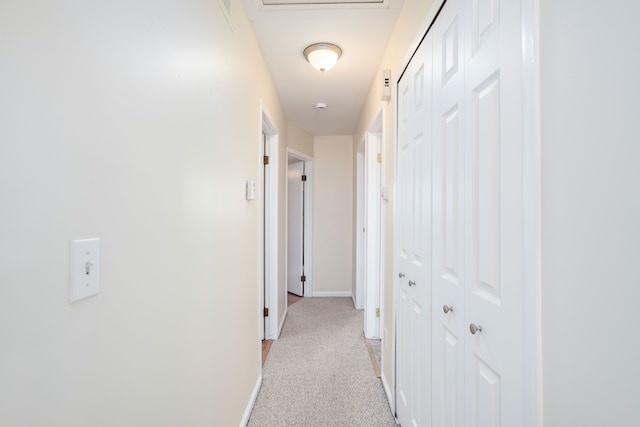 hallway featuring baseboards and light carpet
