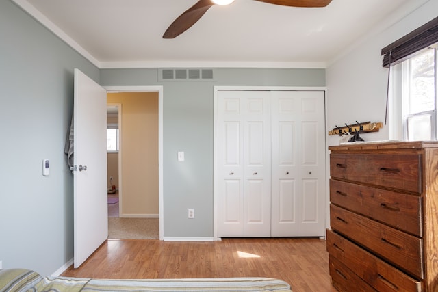 bedroom with visible vents, multiple windows, light wood finished floors, and a closet