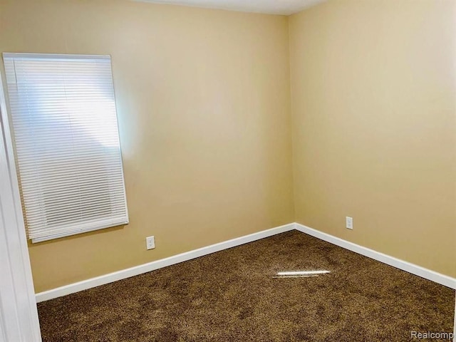 empty room with baseboards and dark carpet