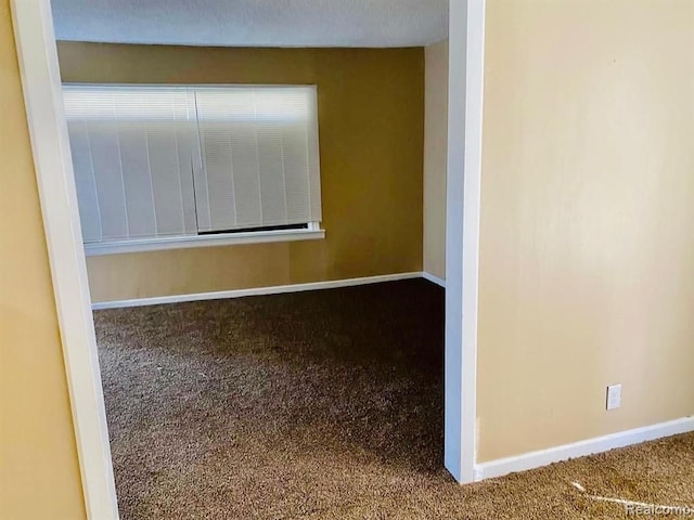 carpeted spare room featuring baseboards