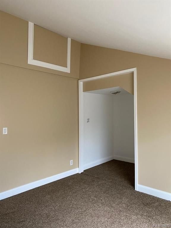 unfurnished room with lofted ceiling, carpet floors, and baseboards