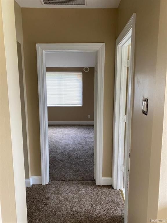 hallway with baseboards, carpet flooring, and visible vents