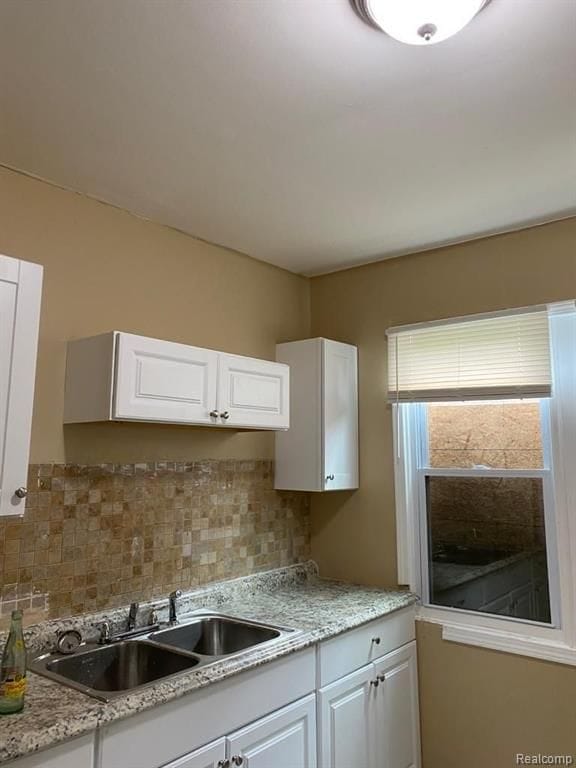 kitchen featuring light countertops, white cabinetry, tasteful backsplash, and a sink