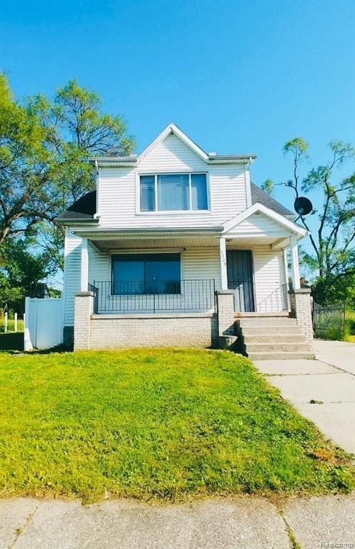 view of front of property featuring covered porch, fence, and a front yard