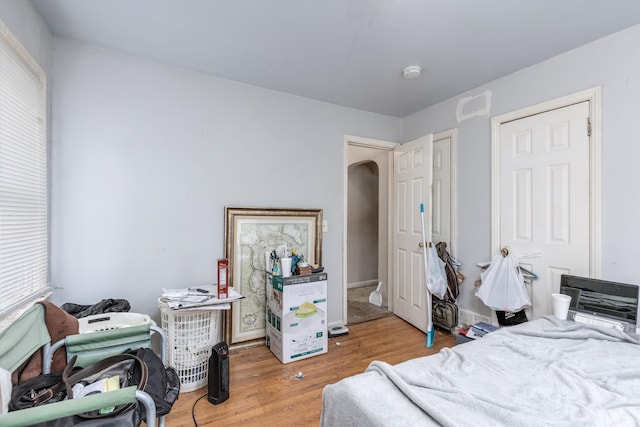 bedroom with arched walkways and wood finished floors