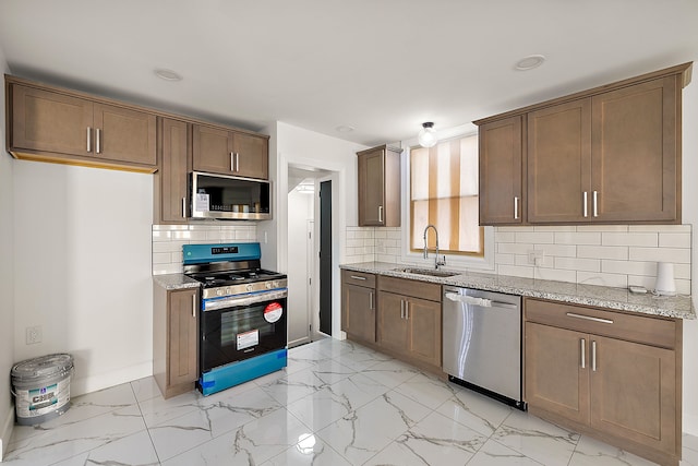 kitchen featuring a sink, light stone counters, stainless steel appliances, and marble finish floor