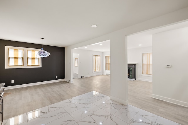 interior space with visible vents, baseboards, a fireplace with raised hearth, light wood finished floors, and recessed lighting