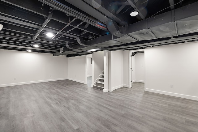 finished below grade area with baseboards, stairs, and wood finished floors