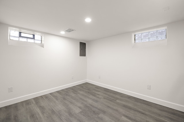 below grade area with recessed lighting, baseboards, dark wood-type flooring, visible vents, and electric panel