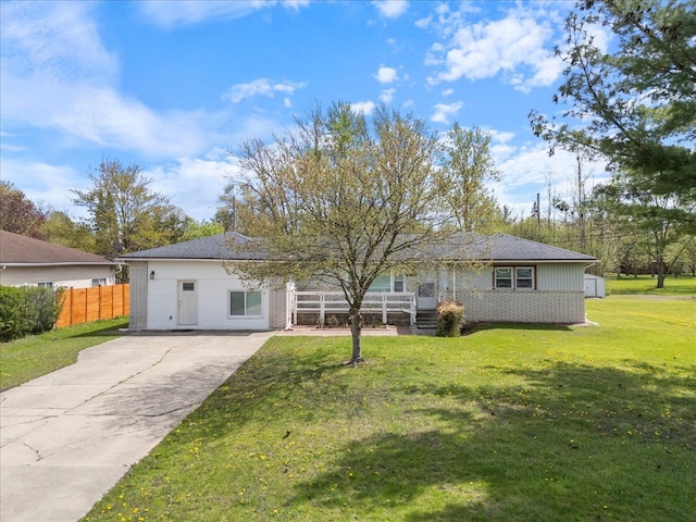 view of front of property featuring fence, concrete driveway, a front lawn, and brick siding