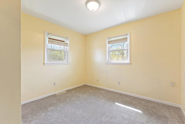 carpeted empty room featuring baseboards and visible vents
