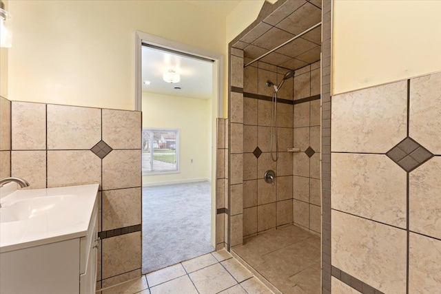 full bathroom featuring vanity, tile patterned flooring, a tile shower, and tile walls