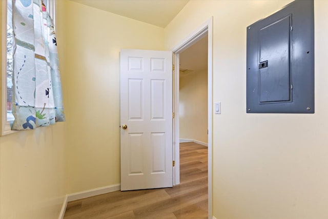hallway with baseboards, electric panel, and wood finished floors