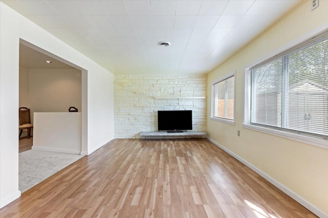 unfurnished living room with baseboards, light wood finished floors, visible vents, and a fireplace