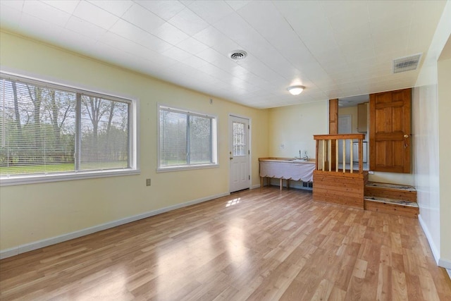 interior space with light wood-type flooring, baseboards, and visible vents