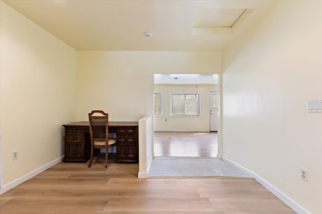 unfurnished office featuring baseboards, attic access, and wood finished floors
