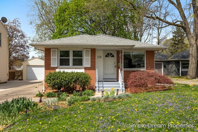 bungalow-style house with a detached garage, brick siding, an outbuilding, and a front lawn