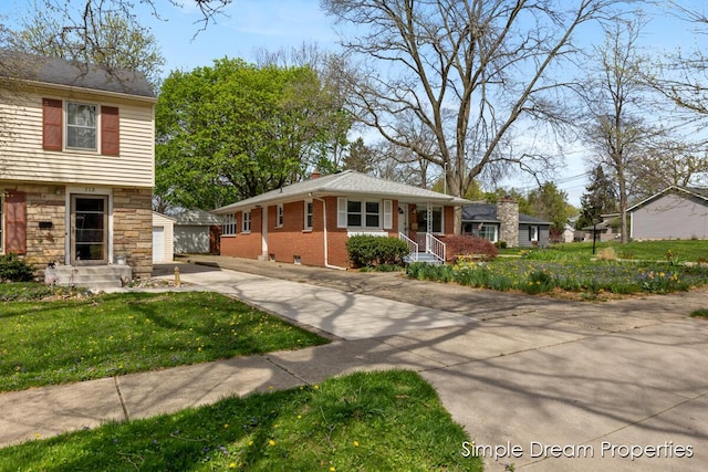 split level home with stone siding, a garage, brick siding, a front yard, and an outdoor structure