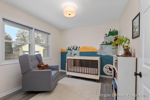 bedroom with a crib, baseboards, and wood finished floors