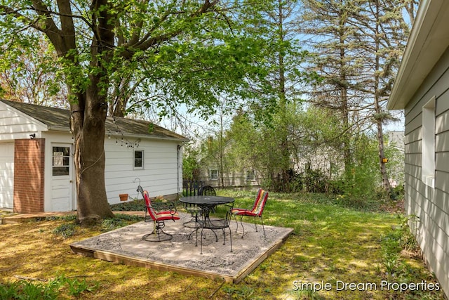 view of yard featuring outdoor dining area, an outdoor structure, and a patio area