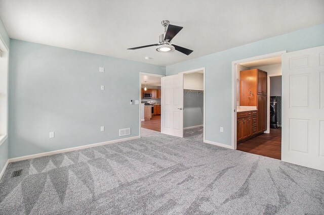 unfurnished bedroom with dark carpet, baseboards, visible vents, and a spacious closet