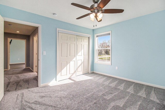 unfurnished bedroom featuring baseboards, ceiling fan, carpet, and a closet