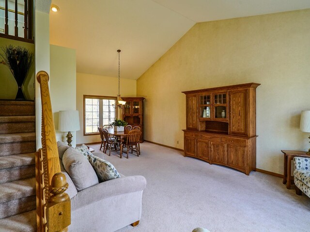 living area featuring baseboards, a chandelier, and light carpet