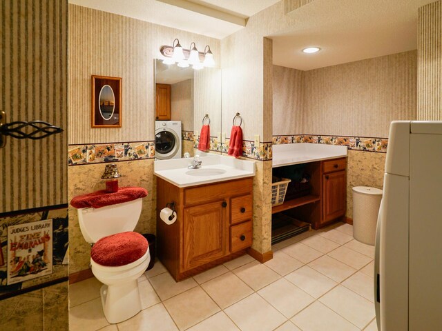 bathroom featuring tile patterned flooring, vanity, toilet, washer / clothes dryer, and wallpapered walls