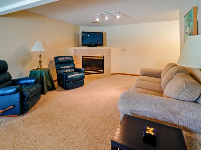 carpeted living area featuring rail lighting, baseboards, and a tile fireplace