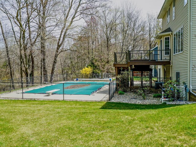 view of swimming pool featuring a lawn, fence, a deck, and a fenced in pool