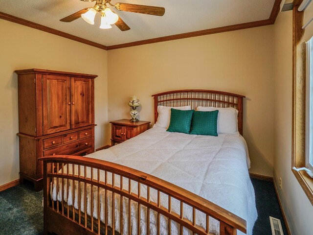 bedroom with dark colored carpet, a ceiling fan, baseboards, visible vents, and ornamental molding
