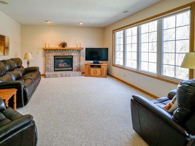living area with carpet flooring, a textured ceiling, baseboards, and a brick fireplace