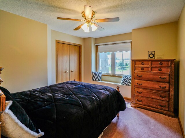 carpeted bedroom with a textured ceiling, ceiling fan, and a closet