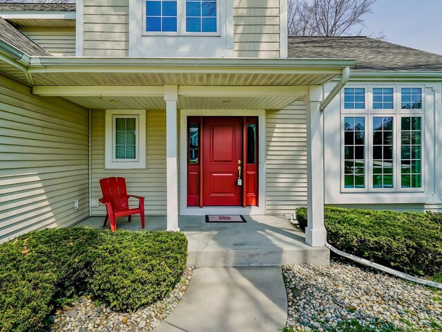 property entrance featuring a shingled roof and covered porch