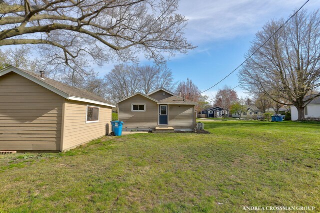 back of property with entry steps and a lawn