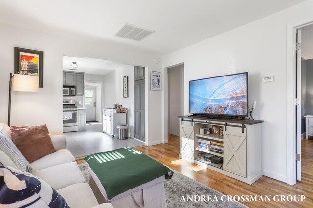 living room featuring baseboards, visible vents, and light wood-type flooring