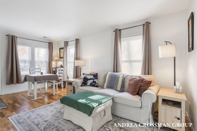 living room featuring baseboards, wood finished floors, and visible vents