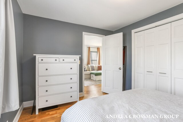 bedroom with light wood-style floors, baseboards, and a closet