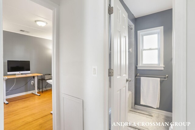 corridor featuring baseboards, visible vents, and wood finished floors