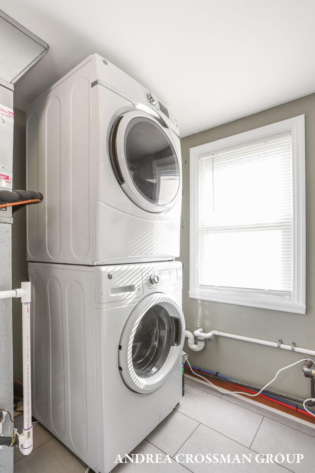clothes washing area featuring laundry area, stacked washer and clothes dryer, and light tile patterned flooring